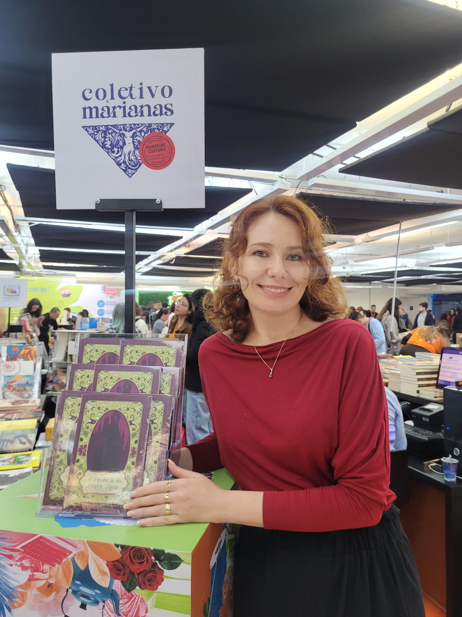 Dayana Barrussi com exemplares do livro no estande do Coletivo Marianas
